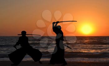 Men silhouettes practicing Aikido at sunrise