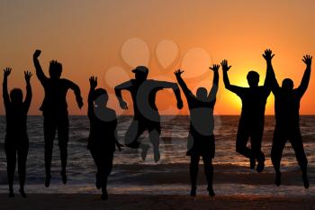 Group of silhouettes of people jumping on beach
