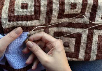 Woman embroidering traditional pattern with geometric design