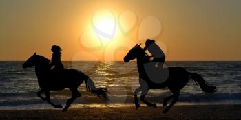 Two horse riders silhouettes galloping on the beach