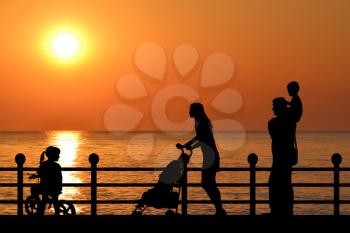 Family silhouette on the waterfront promenade at sunset