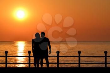 Silhouette of couple on the waterfront at sunrise