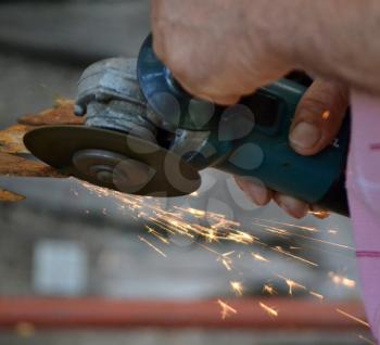 Man working with electric grinder tool on steel pipe and sparks flying