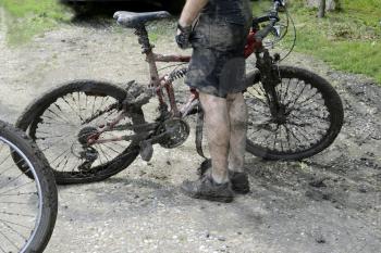 Mountain bike cyclist and dirty bike on a muddy road