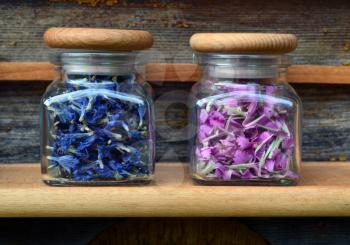 Pink and blue flowers in transparent jars