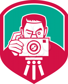 Illustration of a photographer shooting aiming with vintage camera set inside shield crest on isolated background done in retro style. 