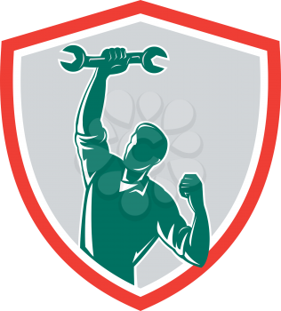 Illustration of a mechanic holding spanner wrench pumping fist set inside shield crest on isolated background done in retro style.