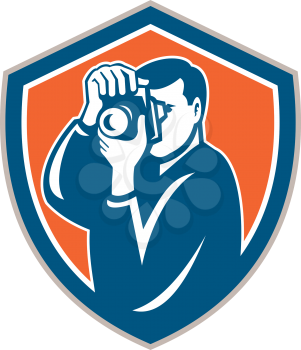 Illustration of a photographer shooting aiming with camera set inside shield crest on isolated background done in retro style.