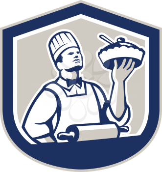 Illustration of a chef, cook or baker holding up pie pastry with roller in foreground  facing front set inside shield crest on isolated background done in retro style.