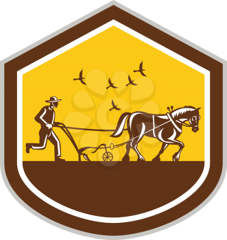 Illustration of farmer and horse plowing famr field viewed from side set inside shield shape done in retro woodcut style on isolated background.