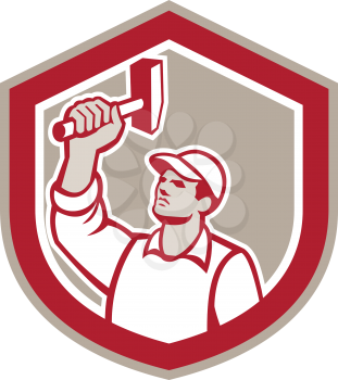 Illustration of a union worker wielding a hammer looking up set inside shield crest shape done in retro style.