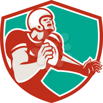 Illustration of an angry american football player holding ball looking up set inside shield crest on isolated background done in retro style. 