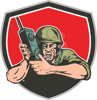 Illustration of a World War two American soldier serviceman holding field radio walkie-talkie viewed from front set inside shield on isolated background done in retro style. 