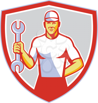 Illustration of a mechanic wearing hat holding wrench facing front set inside shield crest on isolated background done in retro style. 