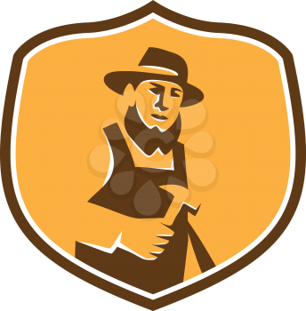 Illustration of an amish carpenter builder wearing hat holding hammer faciing front set inside shield crest on isolated background done in retro style. 