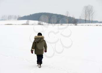 Royalty Free Photo of a Boy Walking in a Snowy Landscape