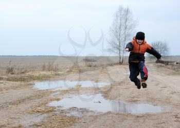 Royalty Free Photo of a Boy Jumping Over a Puddle