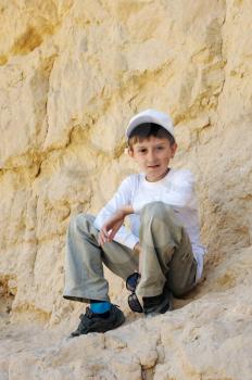 Royalty Free Photo of a Boy Sitting on a Rocky Wall