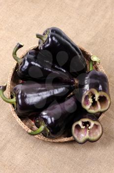 Royalty Free Photo of Black Peppers in a Basket With One Cut