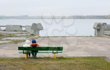 Royalty Free Photo of Children on a Bench at the Lake on an Overcast Day