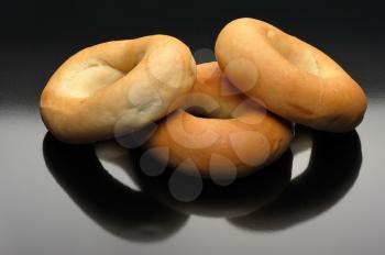 Three bagels and their reflection on a black background