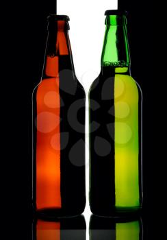 Bottles of lager beer from green and brown glass, isolated on a black and white background.