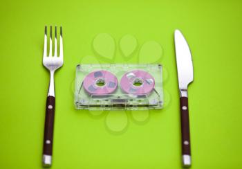 Royalty Free Photo of an Audio Tape Between a Fork and Knife