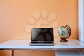 Royalty Free Photo of a Desk With a Globe and Laptop