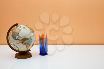 Royalty Free Photo of a Desk With a Globe and Pencils in a Holder