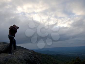 Royalty Free Photo of a Person Taking a Picture on Top of a Rise at Dusk With an Overcast Sky