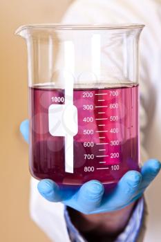 Scinetist Hand holding Chemistry lab beaker with permanganate