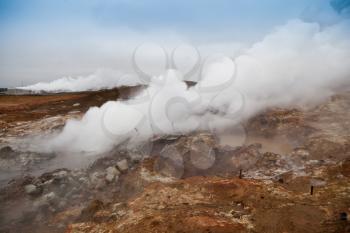 Desolate landscape of Iceland volcanic brown soil with steamy geyser mist and grey colored sky