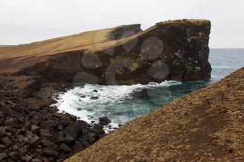 Rocky cliff with grass on Iceland Reykjanes peninsula volcanic stones shore coast line landscape