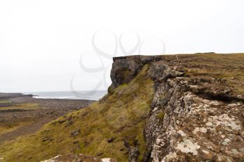 Rocky cliff with grass on Iceland Reykjanes peninsula volcanic stones shore coast line landscape