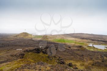 Iceland lighthouse Reykjanesviti with rocky volcanic soil gesers and grey sky landscape