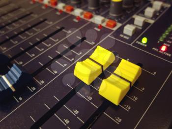 Audio mixing console board channel yellow knobs and buttons closeup

