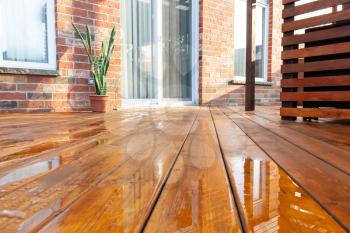 Backyard wooden deck floor boards with fresh brown stain, angled view