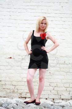 Blonde female fashion model in sexy dress against a brick wall background