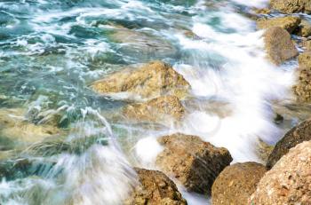 The rock on seashore with water and coming wave (long exposure)..