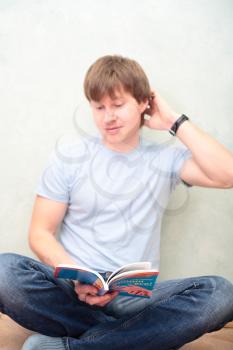relaxed man sitting on the floor with book
