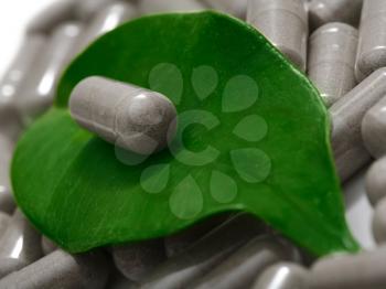 herbal medicine - pill on green leaf over film of pills