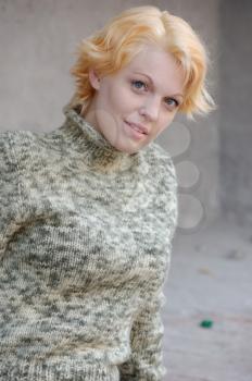 Blonde woman in a green sweater posing outdoors