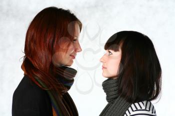 two beautiful redhead and brunette girls with scarf on gray