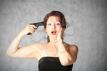suicide - portrait of sexy redhead with pistol on the grey background