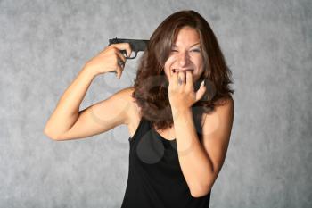 suicide - portrait of sexy brunette with pistol on the grey background