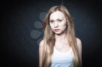 Portrait of a young blond lady on black background