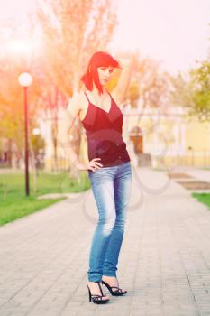 youn pretty girl is posing against park and building