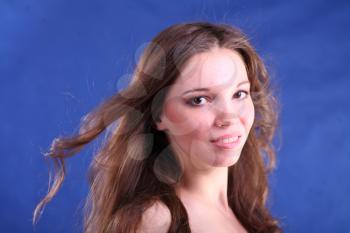 Studio portrait of a beautiful young brunette woman face on blue