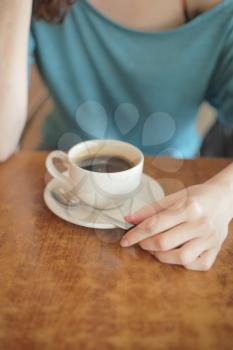 Cup of coffee in the women's hand on table 