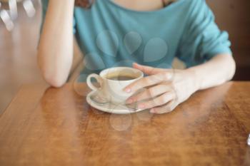 Cup of coffee in the women's hand on table 